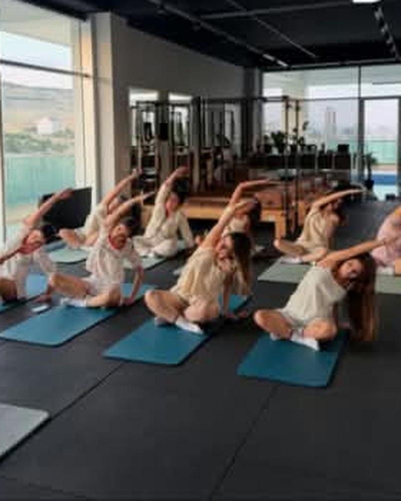 Grup mat pilates dersinde esneme hareketi yapan katılımcılar